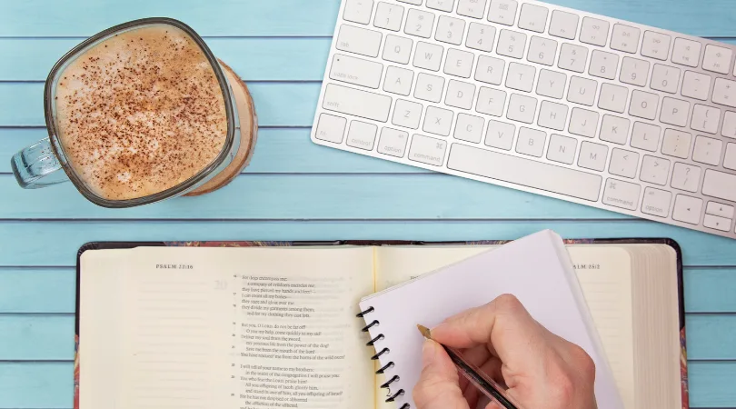 image of an open Bible and someone writing in a journal